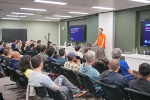 Matt in an orange Astro Launch t-sirt presenting about live collections and route caching.
