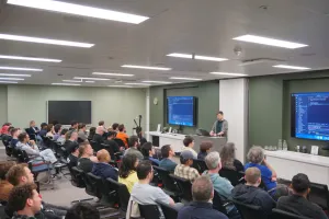 Alex doing a live demo on stage in front of several rows of attendees.